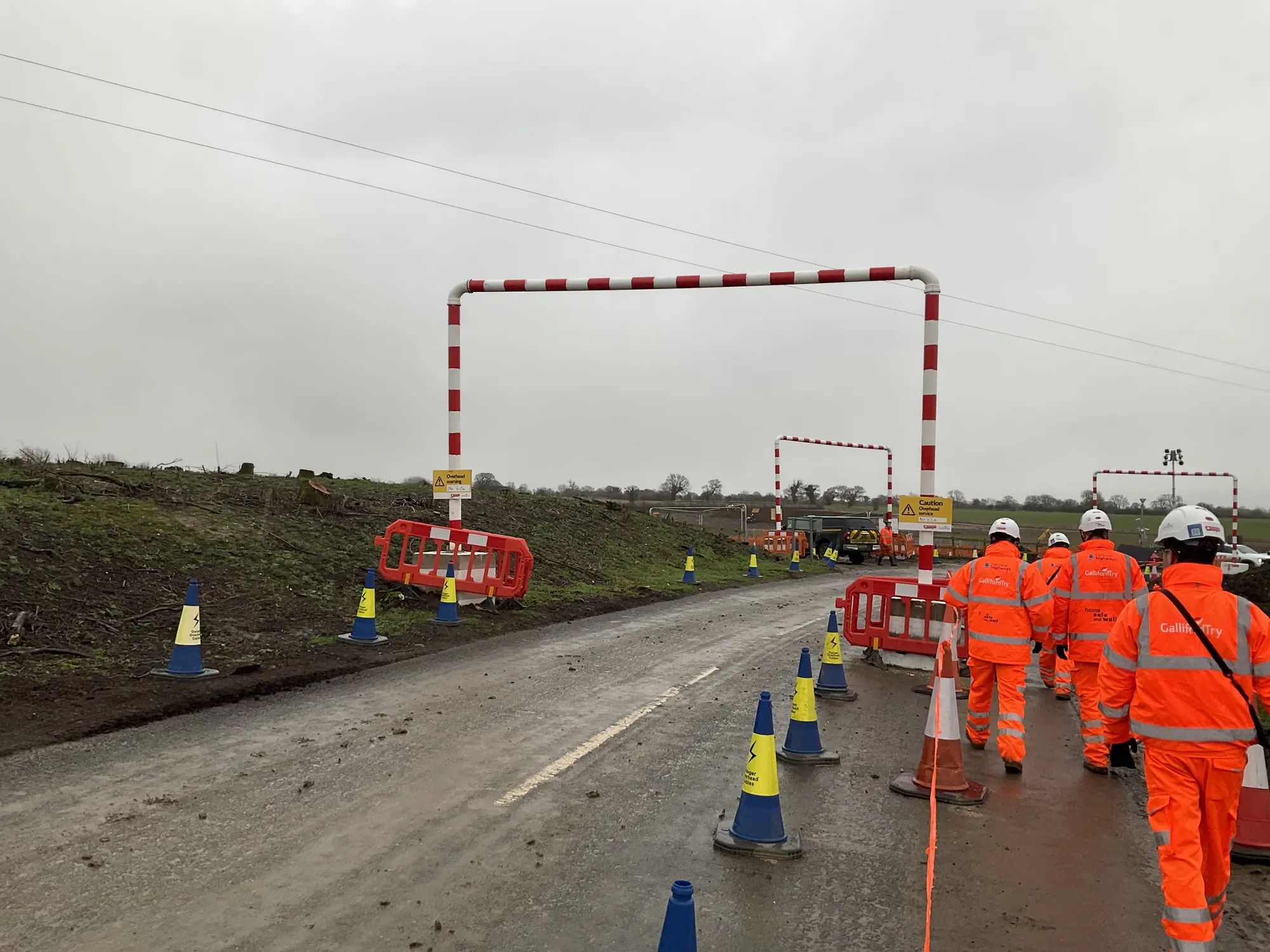 Roadworks crew in hi-vis walking along a closed road towards height barriers