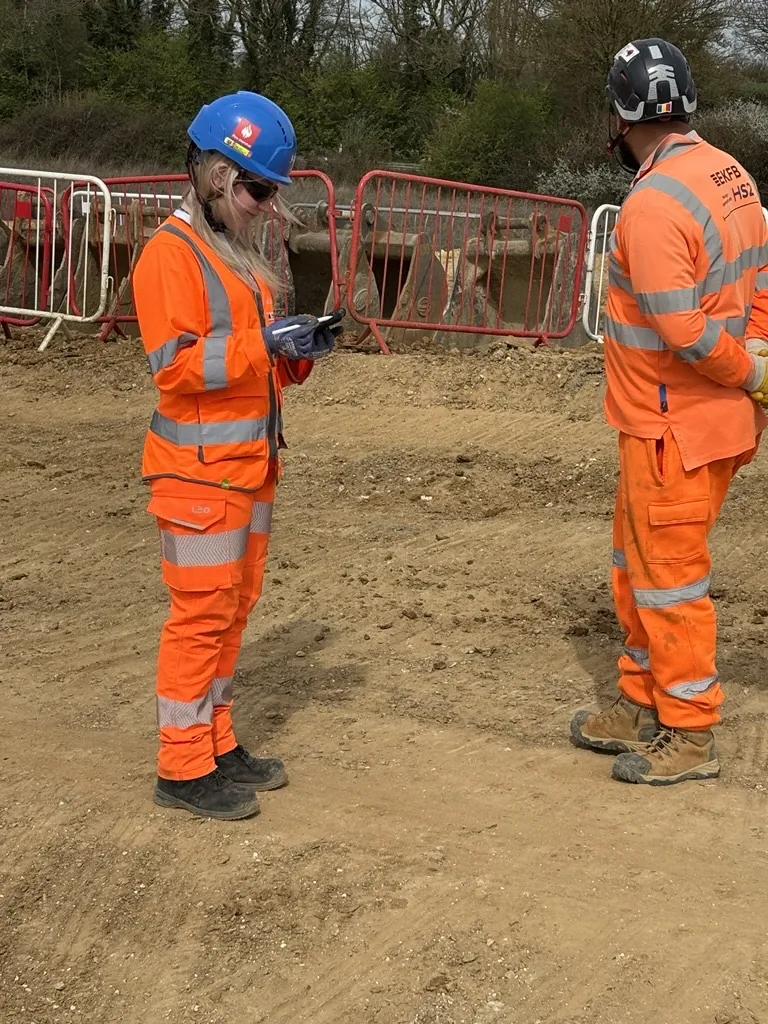 Roadworker in hi-vis recording details on a handheld device on site